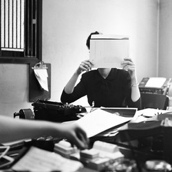 a woman in an office holds a folder covering her face