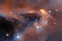 A nebula made up of cloudy gas and dust in the form of soft and wispy clouds, dotted with stars