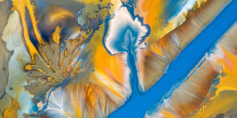 Mining waste, seen from above, forms colorful shapes and channels in the landscape.