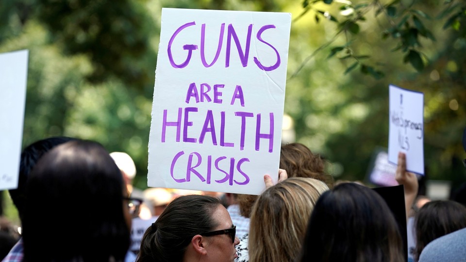 Protester holding a sign that says "Guns are a health crisis"