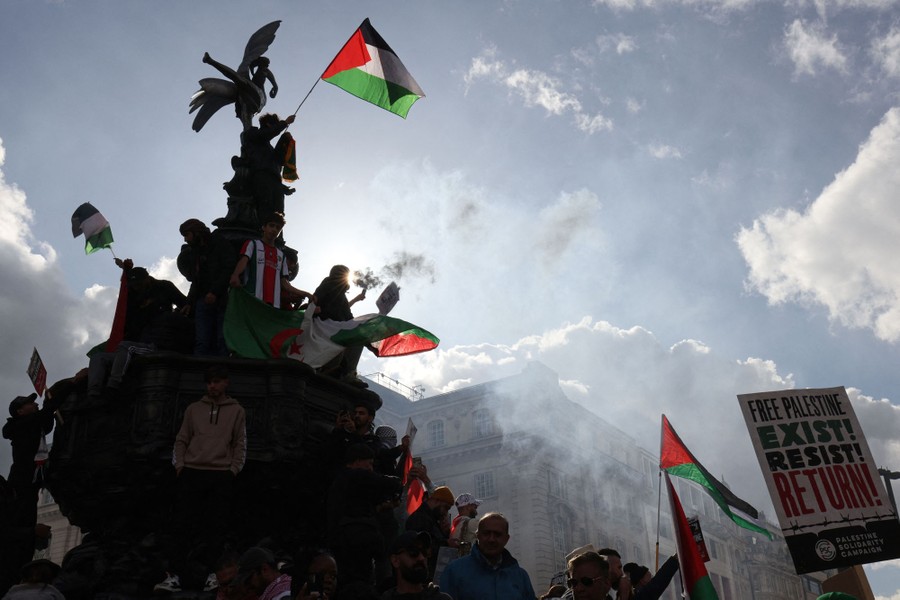 Protesters holding Palestinian flags climb the Eros statue, at Piccadilly Circus, London.