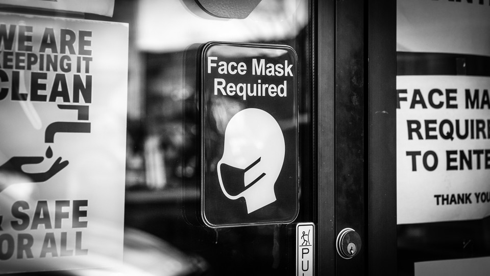 Signs requiring face masks and COVID-19 protocols on a restaurant window in Plymouth, Michigan