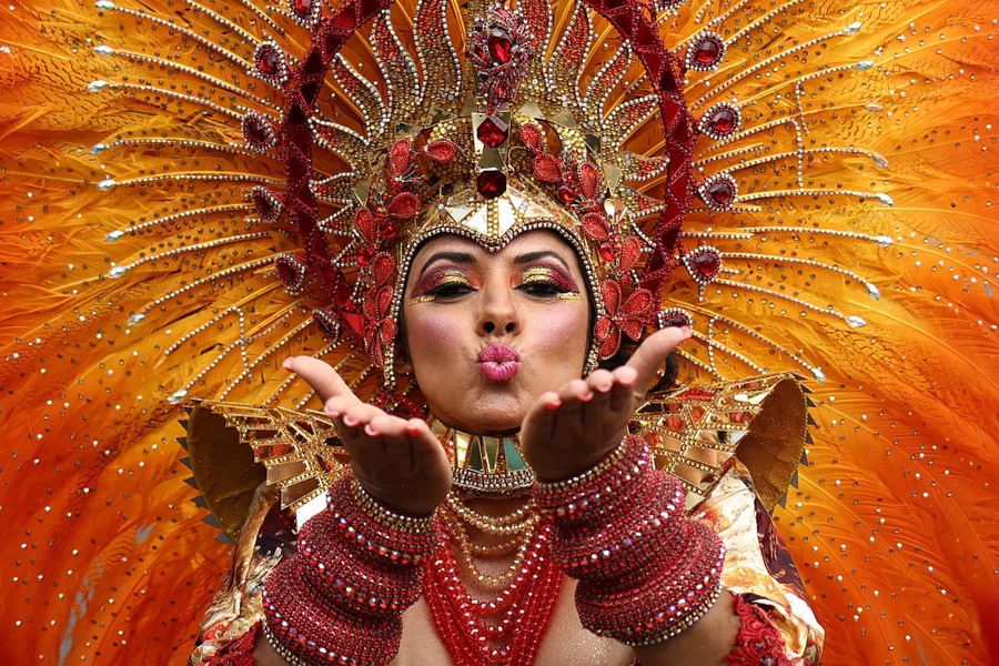 A performer in a large feathered costume blows a kiss to the camera.