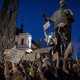 Photograph of Ukrainians protesting near the monument of a poet, holding up homemade cardboard signs