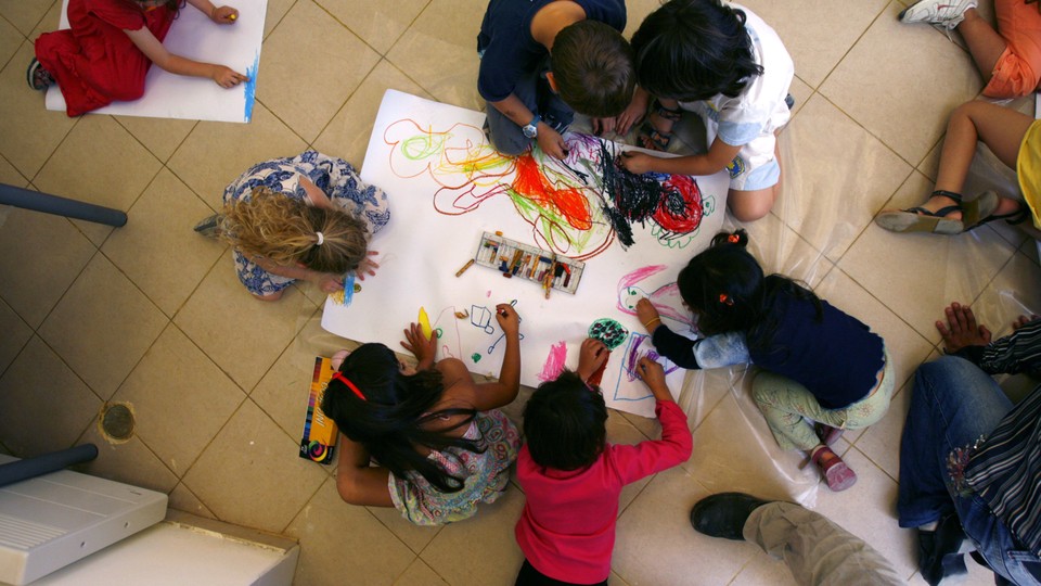 An overhead view of six pre-schoolers coloring.