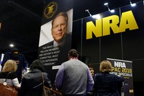 People in front of a booth with a picture of Wayne LaPierre and the NRA logo