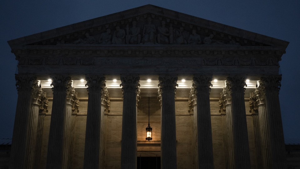 Photograph of the Supreme Court building at dusk with a hanging lantern and lights illuminating the entrance