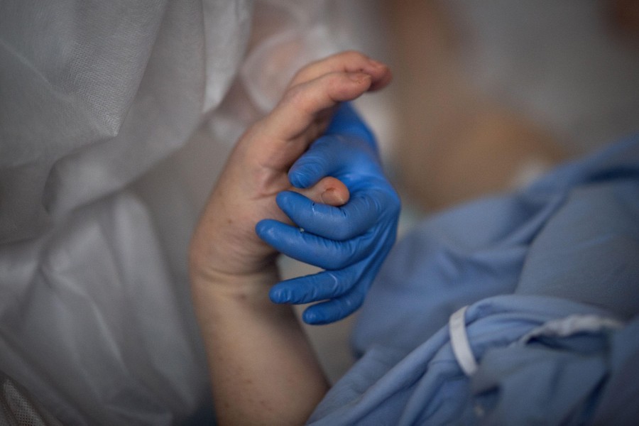 A medical worker holds the hand of a patient.