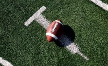 A football on a field, painted with the shape of a syringe