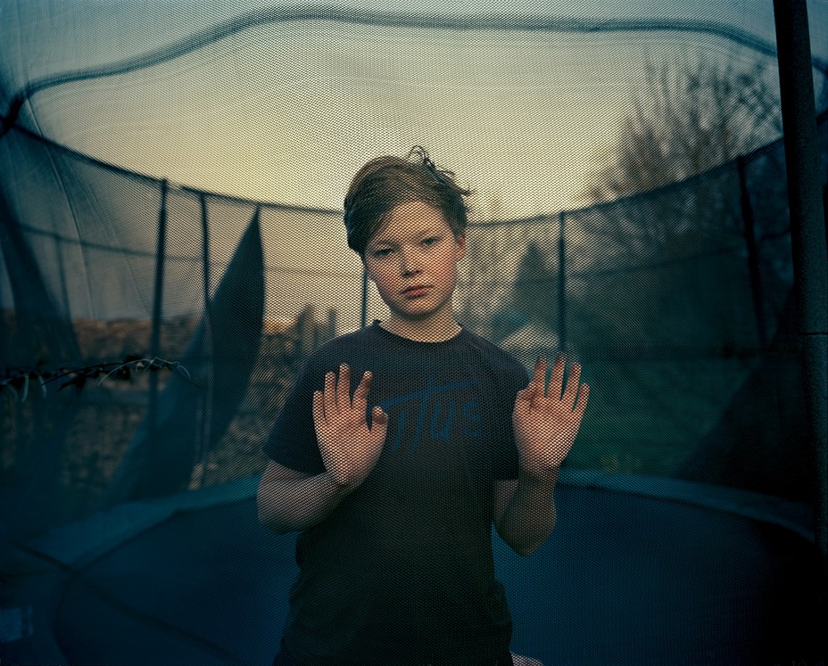 boy on trampoline places his hands against the net surrounding it