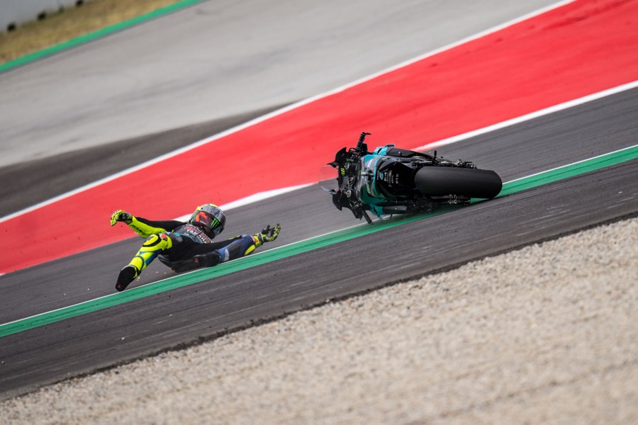 A motorcycle rider and his motorcycle slide across a track after a crash.