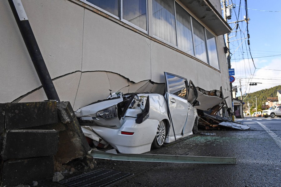 A crushed car under part of a collapsed building following an earthquake