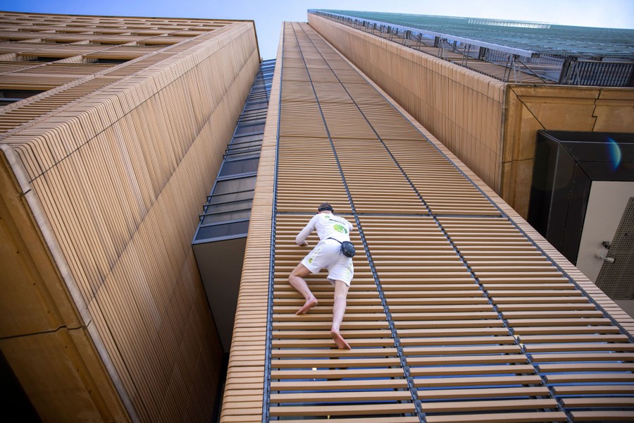 A person begins to climb the outside of a very tall building.