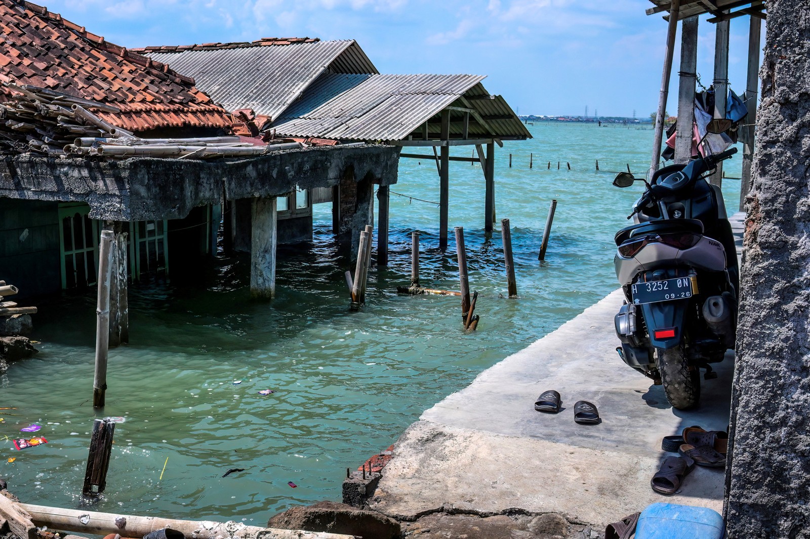 A view of some abandoned and partially-submerged houses, surrounded by seawater.