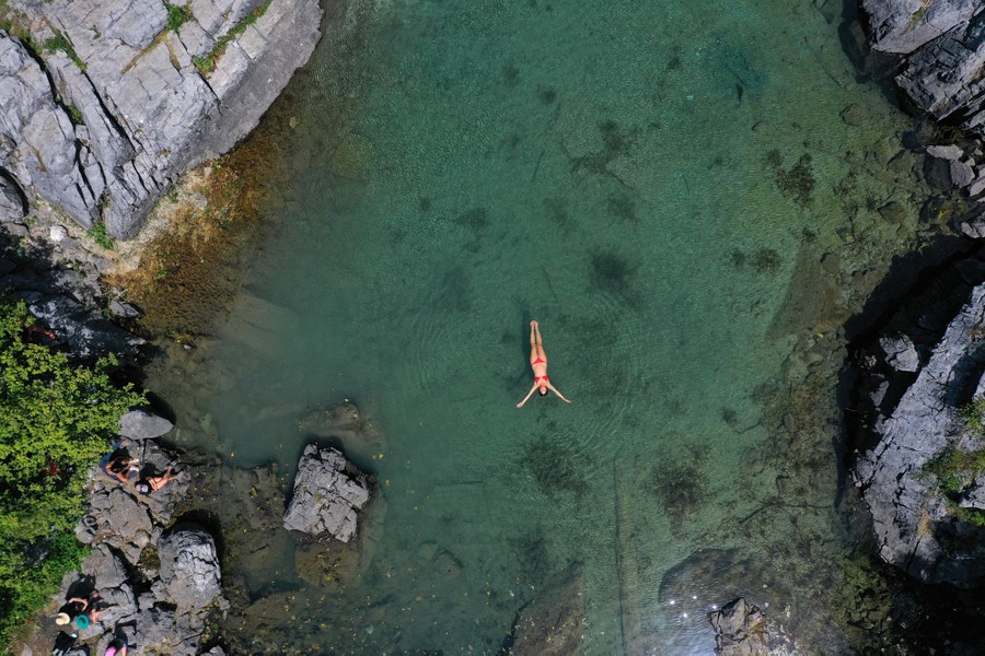 An aerial view of a woman swimming in a small lake.