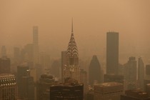 The Chrysler Building and other New York skyscrapers stand beneath an orange, smoky sky.