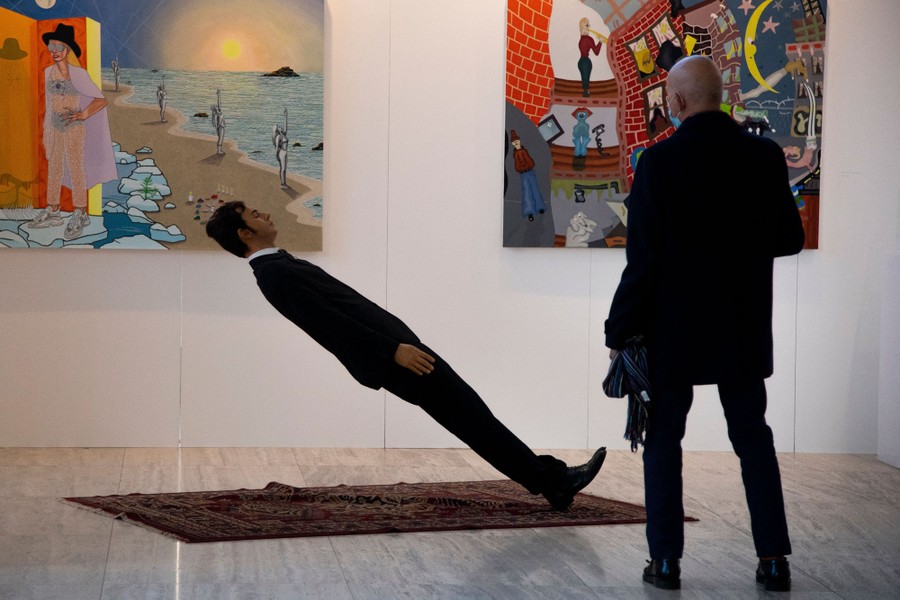 A person walks beside an art installation resembling a falling man.