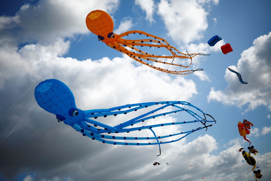 A pair of octopus-shaped kites fly in a cloudy sky.