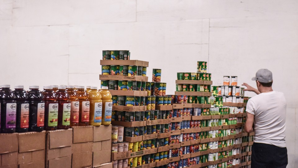 A worker stacks canned food inside a food distribution center