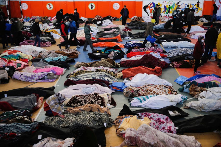 Dozens of bodies wrapped in blankets lie on the floor of a sports hall.