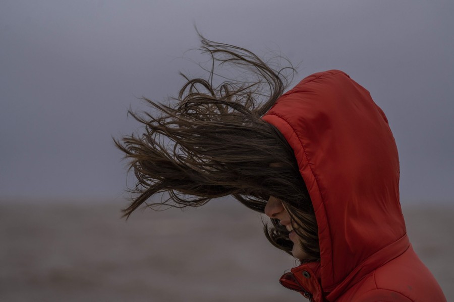 A person's hair blows on a windy day.