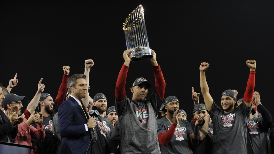 The Boston Red Sox manager Alex Cora hoists the Commissioner's Trophy after defeating the Los Angeles Dodgers in Game Five of the 2018 World Series at Dodger Stadium.