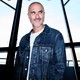 A color photograph of Zane Lowe in front of a wall of windows