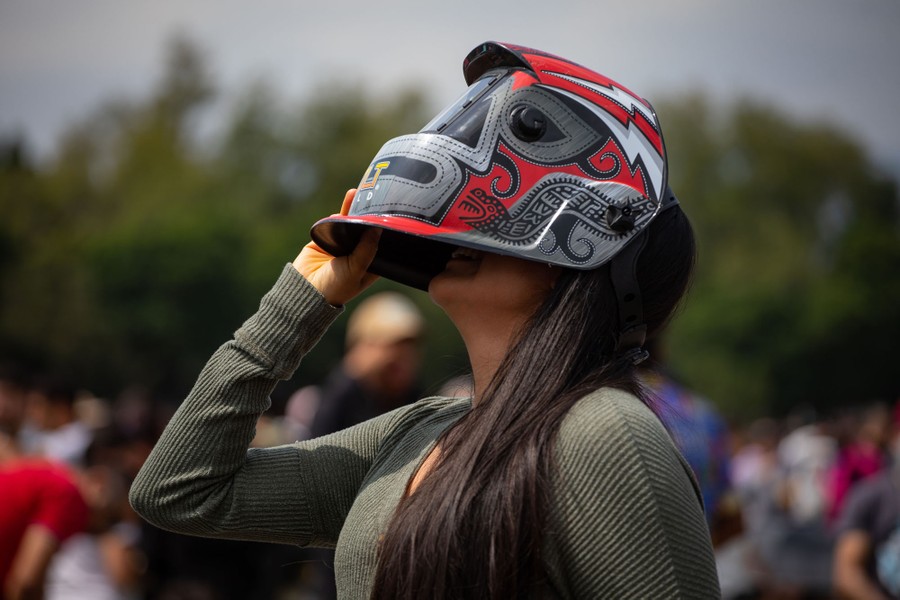 A person looks skyward while wearing a decorated welder's mask.