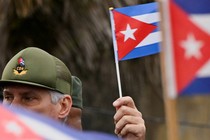 A man in a CDN cap holds a Cuban flag