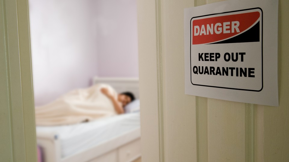 A door with a quarantine sign on it open to reveal a person in bed