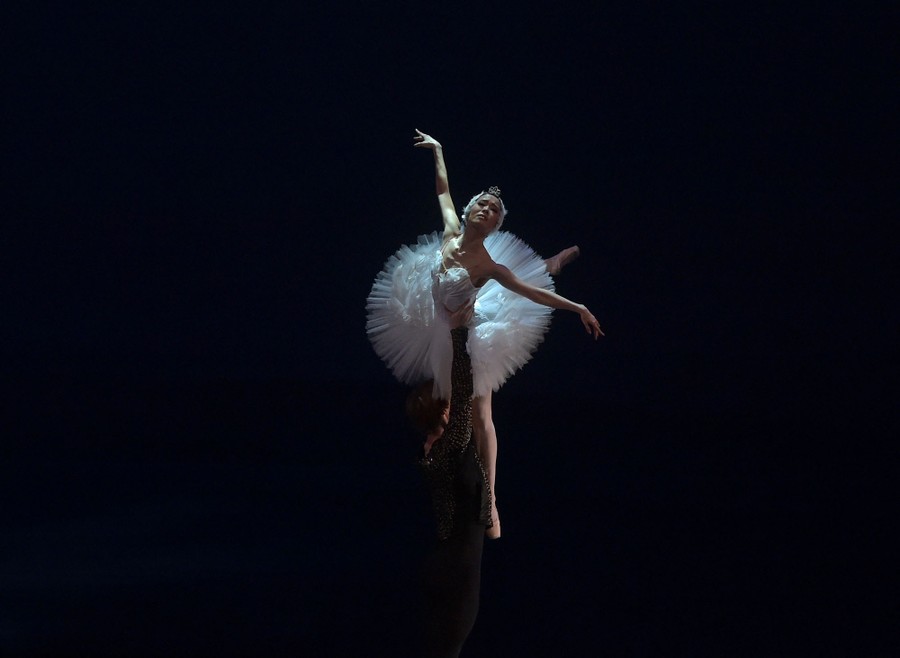 A dancer holds another dancer aloft during a ballet rehearsal.
