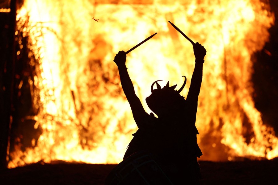A drummer performs as a large wicker figure goes up in flames.