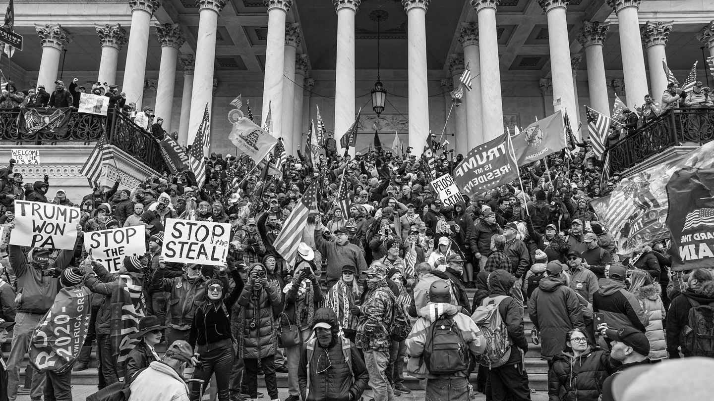 A black and white photo of a pro-Trump mob amassed outside the Capitol on January 6, 2021