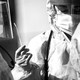 A black and white photo of two health care professionals in medical protective gear holding a cotton swab.
