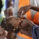 An adult administers an oral vaccine to a baby.