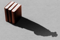 The shadow of three books forms the outline of a detective