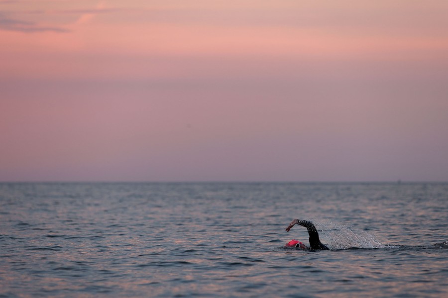 A person swims in an open stretch of water.