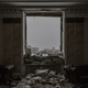 A photograph of a bombed-out room with sandbags piled behind a glassless window
