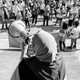 Picture showing an activist wearing a hijab holding a megaphone, speaking to a crowd of protesters holding signs. One of the signs reads: "Free Palestine."