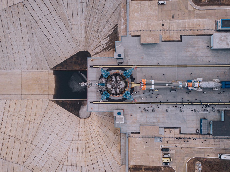 An aerial view of a rocket being moved into place on a launch pad.