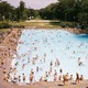 An image of a pool with a lot of people swimming and milling around