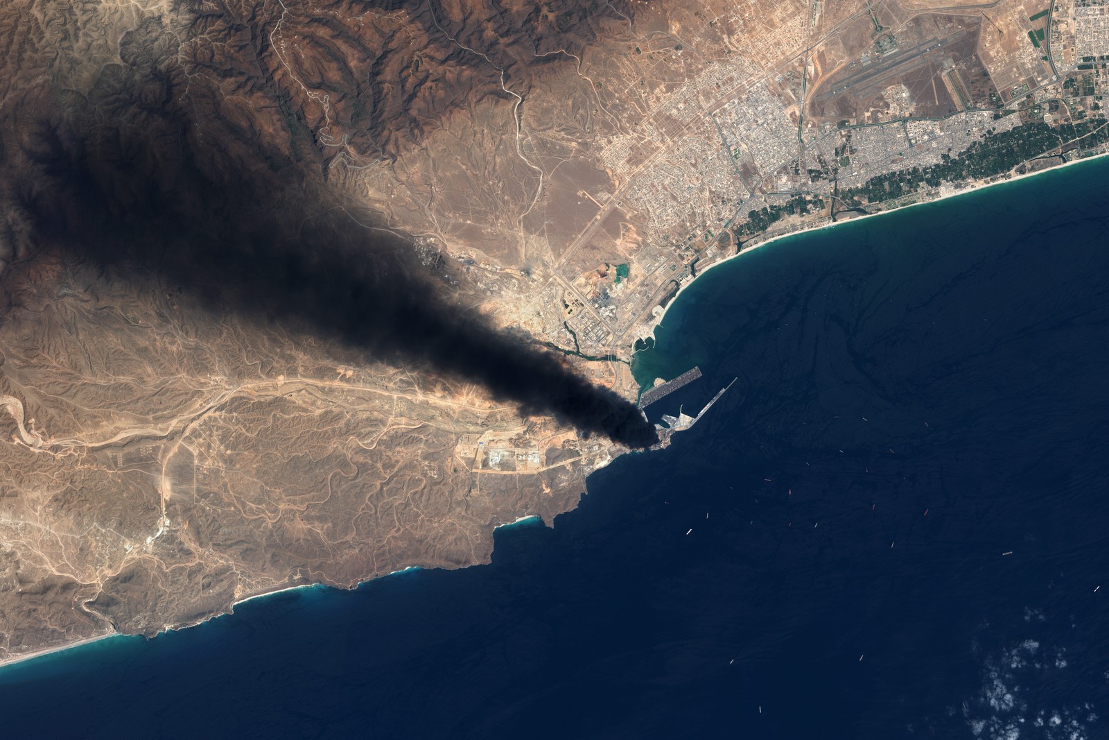 A satellite view of an oil fire, sending a black plume of smoke across the landscape.
