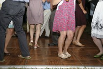 A group of people wearing dresses and slacks dance