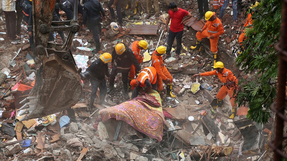 Firefighters and rescue workers search for survivors at the site of the collapsed building on July 25, 2017.