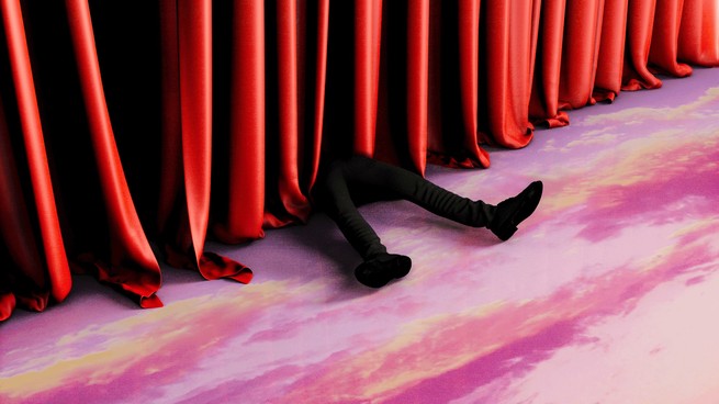 a man's leg's sticking out below theater curtains