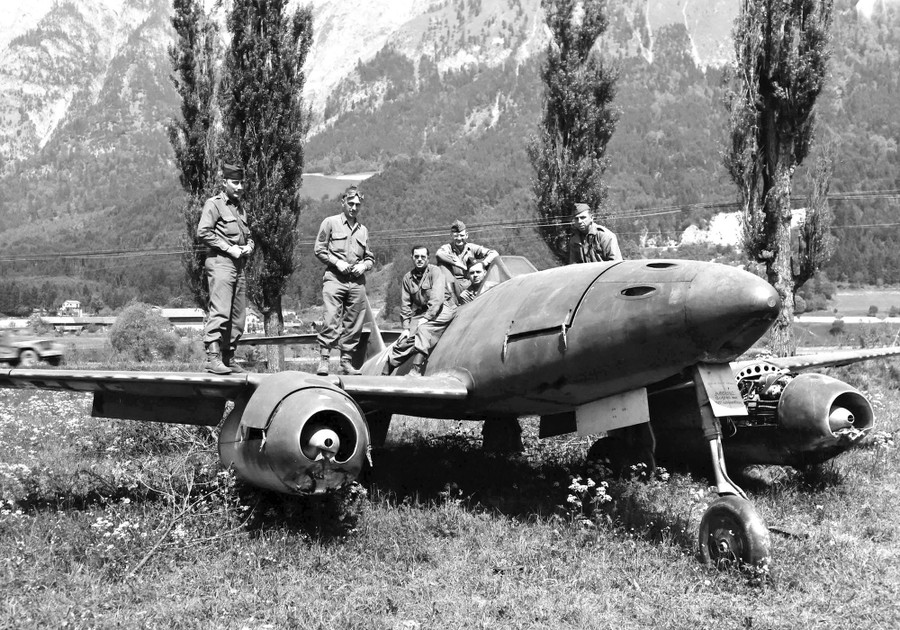 American soldiers pose atop an abandoned German jet fighter aircraft.