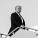 A black-and-white image of Trump looking toward the camera with the presidential seal in the background