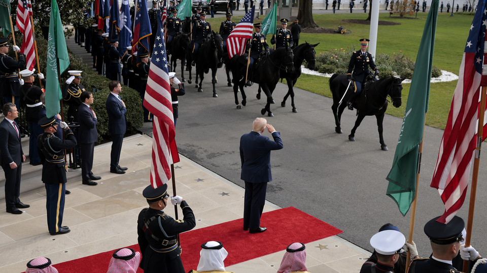 Photograph of Donald Trump saluting a procession of soldiers waving the U.S. and Saudi Arabian flags