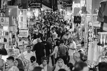 Black and white photograph of people walking through a marketplace in Iran