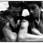 A photo of two young men with tattoos on their arm